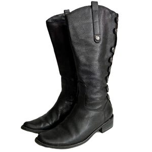 May include: A pair of black leather knee-high boots. The boots have a textured finish and a row of decorative buttons down the side. The boots have a low heel and a rounded toe.