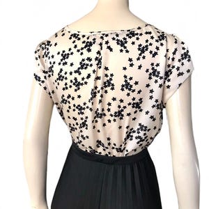 May include: A white top with a black star print and a black pleated skirt.