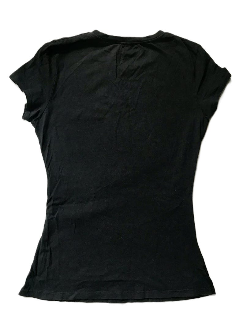 May include: A black, short-sleeved t-shirt with a scoop neck. The shirt is made of a soft, slightly textured fabric. The t-shirt is a solid black color and is likely made of cotton or a cotton blend.