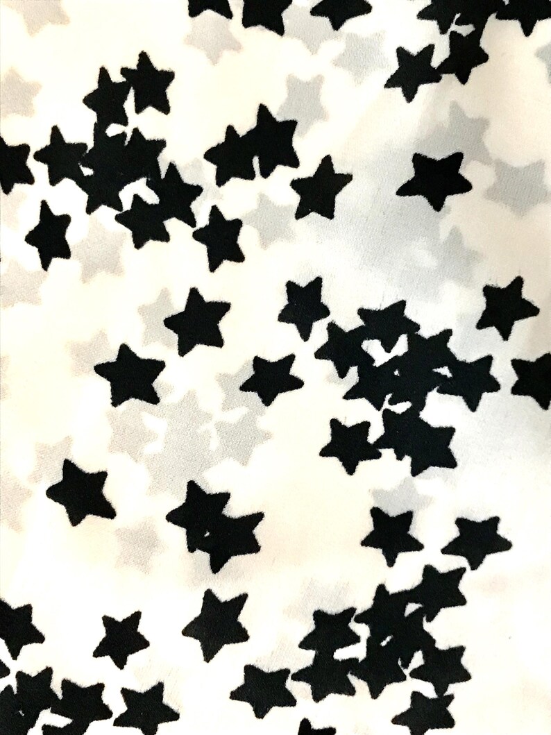 May include: White fabric with a black star pattern. The stars are scattered randomly across the fabric.