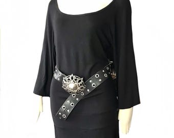 May include: A black, long-sleeved, scoop-neck dress with a black leather belt with silver studs and a large silver buckle.