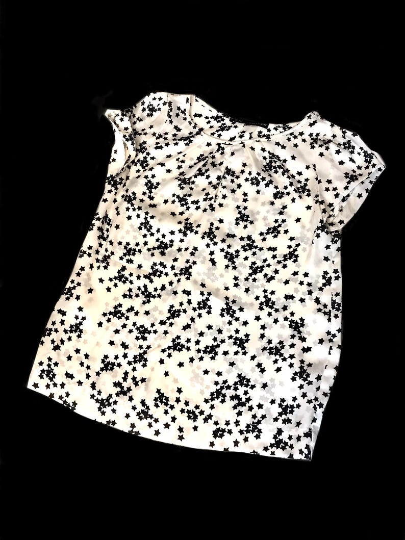 May include: White short-sleeved shirt with a black star print.