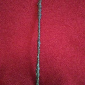 May include: A dark brown wooden wand with intricate carvings and a pointed tip.