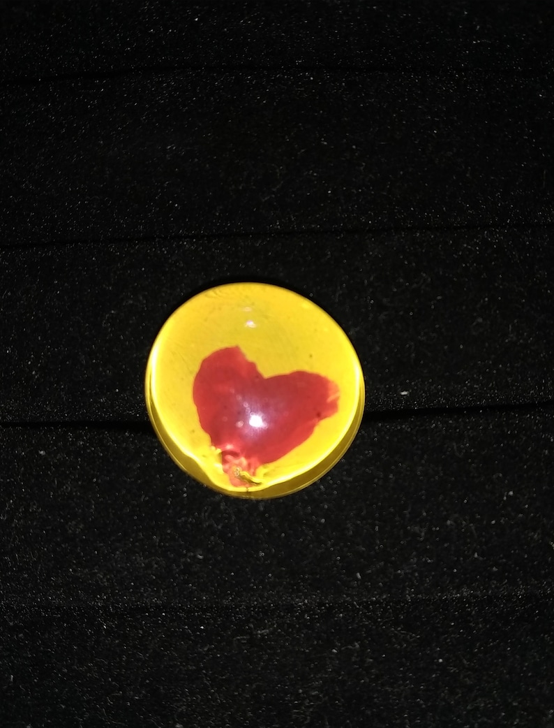 May include: A yellow glass paperweight with a red heart design.