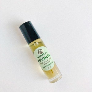May include: A clear glass roller bottle with a black cap and a green label that reads "VISIONS Co. ROSEMARY ESSENTIAL OIL ROLLER SHOPVISIONS.CO.COM 10 ML".