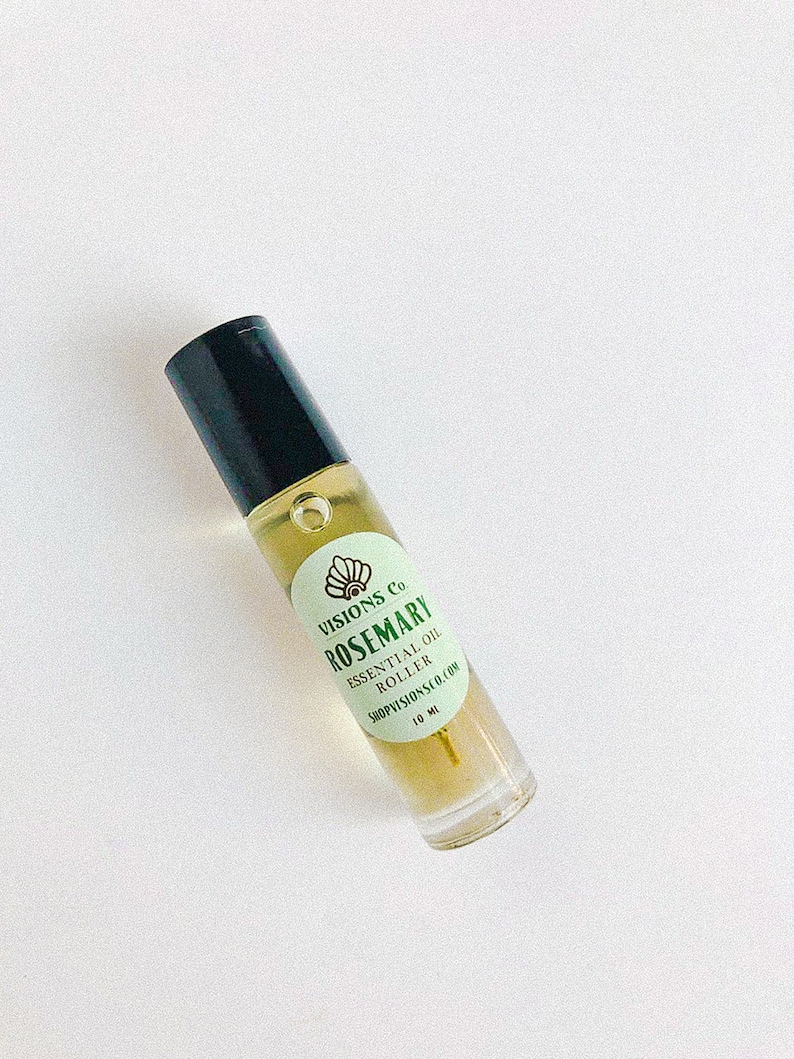 May include: A clear glass roller bottle with a black cap and a green label that reads "VISIONS Co. ROSEMARY ESSENTIAL OIL ROLLER SHOPVISIONS.CO.COM 10 ML".