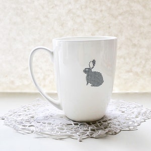 May include: White ceramic mug with a black and white geometric rabbit design.