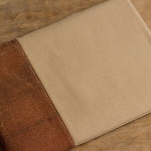 K&ouml;nnte beinhalten: Eine braune und beige Laptop-H&uuml;lle aus Stoff mit einer Naht in der Mitte.