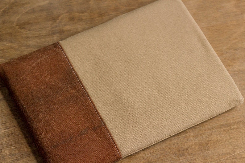 K&ouml;nnte beinhalten: Eine braune und beige Laptop-H&uuml;lle aus Stoff mit einer Naht in der Mitte.