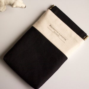 以下が含まれることがあります： ジッパー付きの黒と白のキャンバスポーチ。ポーチには「POCHETTE GAVOTTE PARIS」の文字が前面に印刷されています。