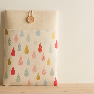 May include: A beige laptop sleeve with a flap closure and a wooden button. The sleeve is lined with a fabric featuring a repeating pattern of colorful raindrops.