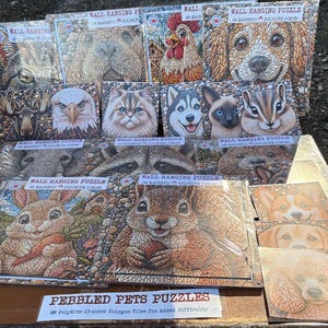 May include: A selection of "Pebbled Pets Puzzles" showing a dog, cat, and squirrel. Each "Wall Hanging Puzzle" contains 89 magnetic tiles. The puzzles have a textured, pebble-like design. The text reads "89 PolyKite 13-sided Polygon Tiles".