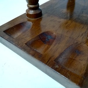 May include: Wooden stand with four round indentations for holding pipes. The stand is made of dark brown wood and has a smooth, polished finish.