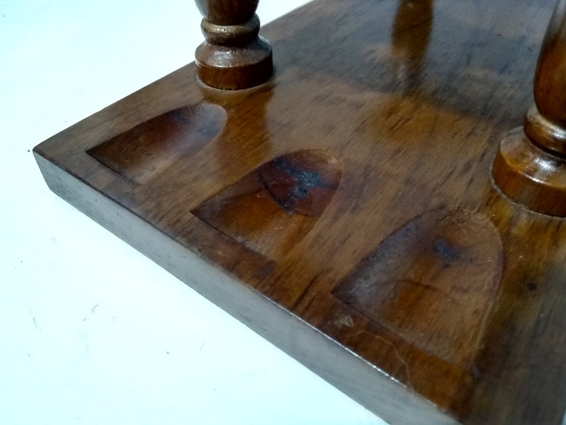 May include: Wooden stand with four round indentations for holding pipes. The stand is made of dark brown wood and has a smooth, polished finish.