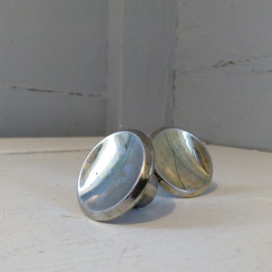 May include: Two silver-toned round cabinet knobs with a slightly domed shape.