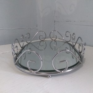 May include: A silver oval tray with a mirrored surface and a decorative scrolled border.