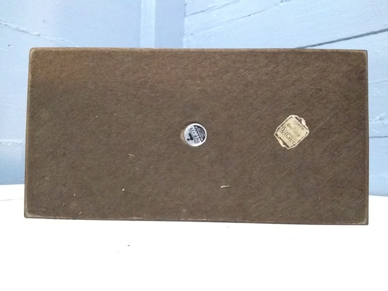 May include: The bottom of a wooden box with two round stickers. One sticker says "Genuine Walnut" and the other says "Made in USA".