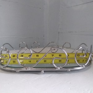 May include: A silver oval tray with a mirrored surface and a decorative scrolled metal rim. The tray is 9 inches long.