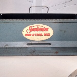 May include: A blue metal tool box with a white oval label that says "Sunbeam The Best Electric Appliances Made Add-A-Tool Box".