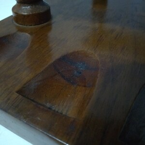 May include: A wooden pipe rack with four slots for pipes. The rack is made of dark brown wood and has a smooth finish.