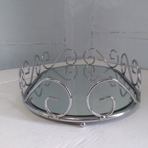 May include: A silver oval tray with a mirrored surface and a decorative scrolled rim.