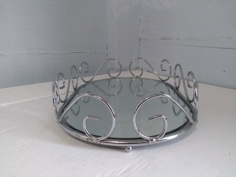 May include: A silver oval tray with a mirrored surface and a decorative scrolled rim.