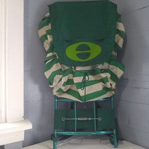 May include: A green and white striped backpack with a green frame and a green oval logo with a white letter "E" inside.