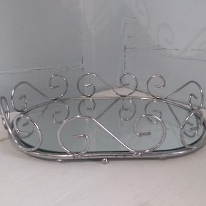 May include: A silver oval tray with a mirrored surface and a decorative scrolled rim.