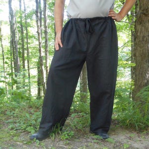 May include: Black drawstring pants with a wide leg and a relaxed fit.