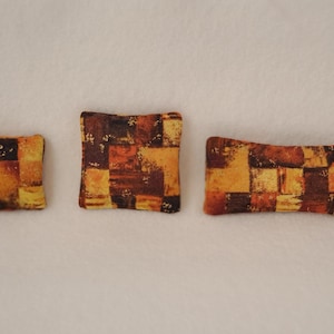 May include: Three decorative throw pillows with a brown, orange and yellow geometric pattern.