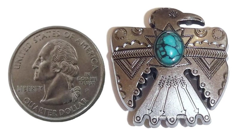 May include: Silver-toned metal Native American eagle pendant with a turquoise stone inlay. The eagle is depicted with outstretched wings and a detailed design.