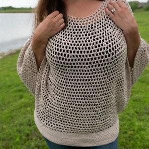 May include: A beige crochet top with a loose, open-weave design. The top has a round neckline and long sleeves.