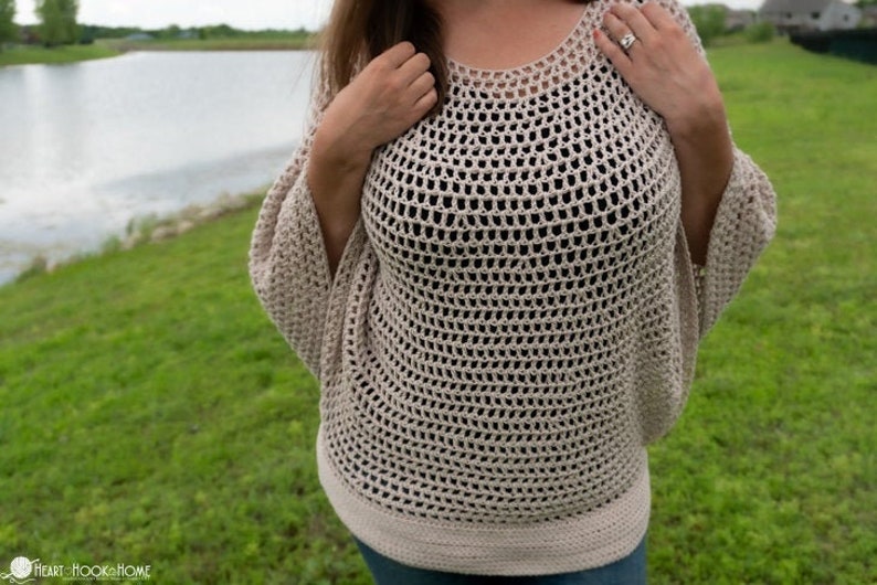 May include: A beige crochet top with a loose, open-weave design. The top has a round neckline and long sleeves.