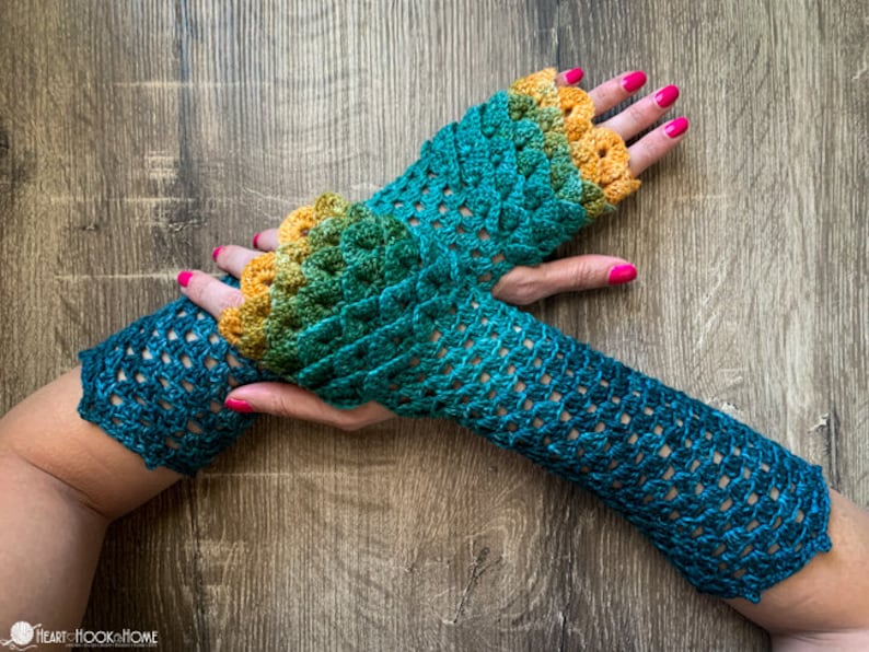 May include: A pair of teal and yellow crochet fingerless gloves with a scalloped edge. The gloves are made with a gradient yarn that transitions from yellow to teal.