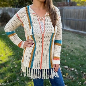 May include: A crocheted sweater with a fringe hem and colorful stripes. The sweater has a tie-up neckline and a relaxed fit.