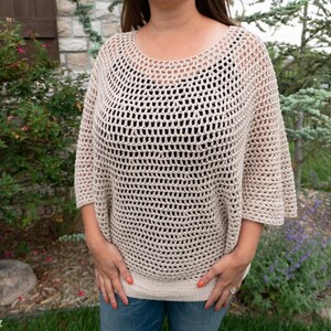 May include: A beige crochet top with a loose, open-weave design. The top has a round neckline and 3/4 sleeves.