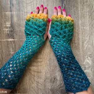 May include: A pair of crocheted fingerless gloves with a gradient colour pattern, transitioning from yellow to green to blue. The gloves have a lacy design and are made with a fine yarn.