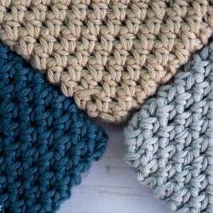 May include: Three crocheted squares in different colours: teal, beige, and light blue. The squares are made with a simple stitch pattern and have a textured look.