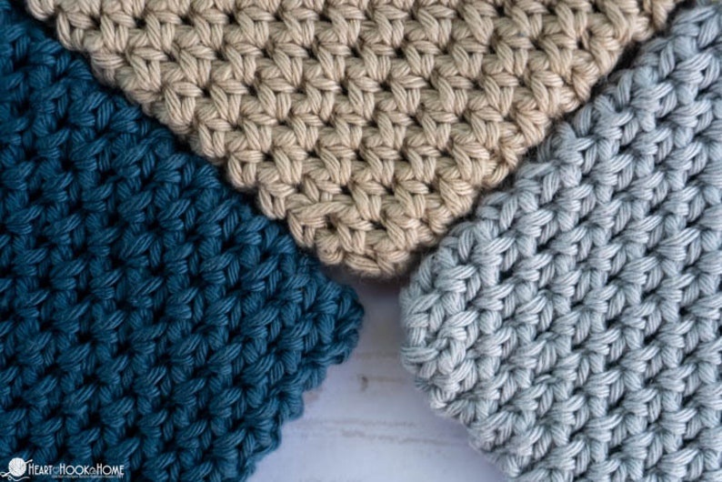 May include: Three crocheted squares in different colours: teal, beige, and light blue. The squares are made with a simple stitch pattern and have a textured look.
