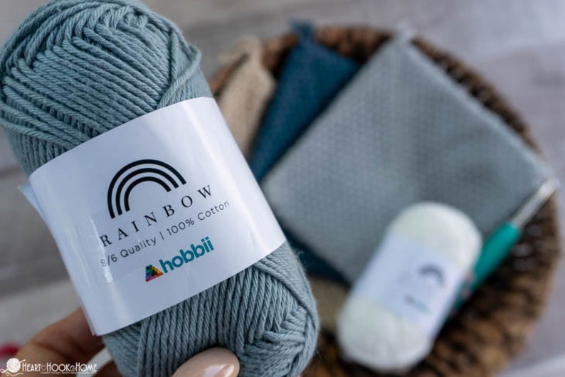 May include: A skein of light blue cotton yarn labelled "Rainbow 8/6 Quality | 100% Cotton" with the hobbii logo.