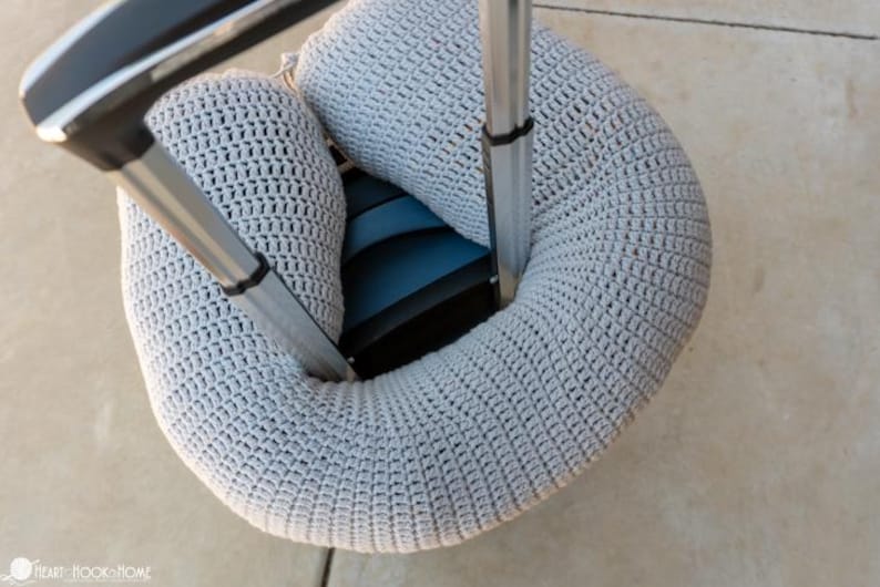 Puede incluir: Una envoltura de ganchillo gris claro para el asa del equipaje, dise&ntilde;ada para adaptarse alrededor del asa de una maleta. La envoltura est&aacute; hecha de una tela texturizada de tejido abierto y est&aacute; envuelta alrededor del asa de una maleta. La maleta es azul y negra.