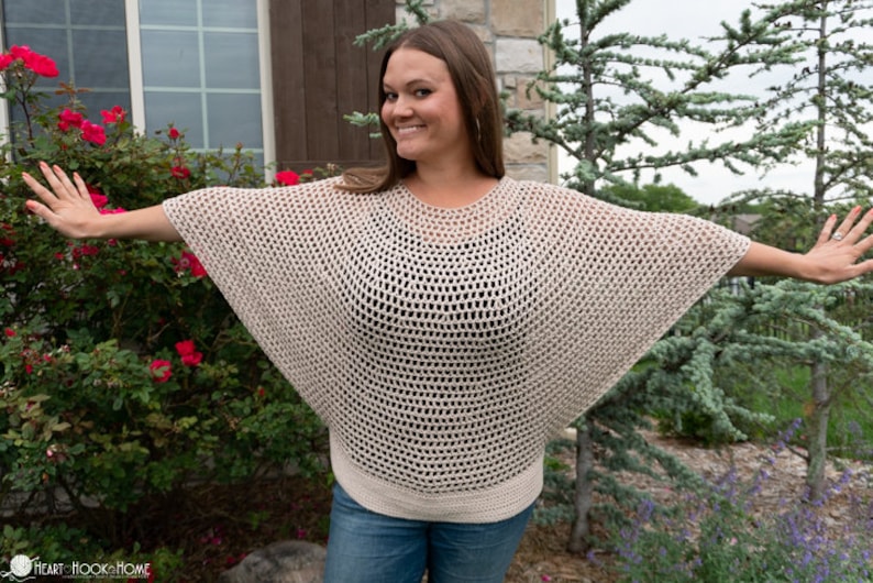 May include: A beige crochet top with a loose, open-weave design. The top has a round neckline and wide, flowing sleeves.