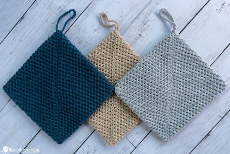 May include: Three crocheted pot holders in teal, beige and grey with a loop handle. The pot holders are made with a textured stitch.