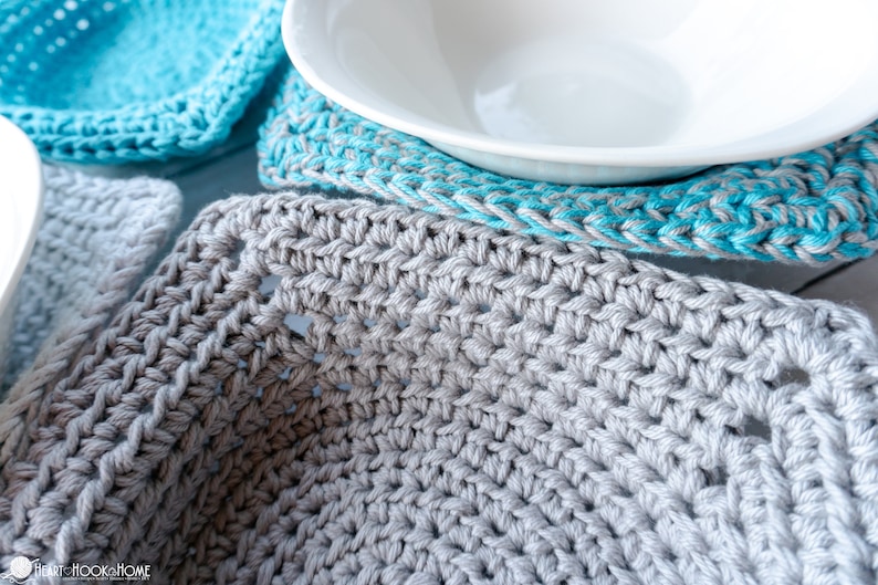 May include: Close-up of a gray crocheted coaster with a white bowl on top. The coaster is made with a simple stitch pattern and has a slightly textured surface.