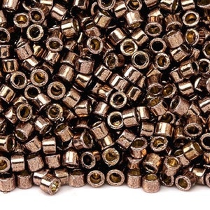 May include: A close-up view of a pile of small, round, copper-coloured beads. The beads have a metallic sheen and are arranged in a random pattern.
