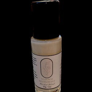 May include: A clear glass roll-on bottle with a black cap. The bottle contains a white cream and has a label that reads "NATURAL DEODORANT Herbal Blend 55g / 2oz".