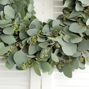 May include: A green eucalyptus wreath with small green buds, ideal for adding a touch of nature to your home decor.