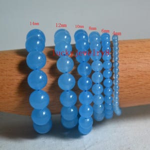Könnte beinhalten: Mehrere Stränge hellblauer Edelsteinperlen in verschiedenen Größen, von 4 mm bis 14 mm. Die runden Perlen sind aufgefädelt und zeigen eine Reihe von Größen für die Schmuckherstellung. Der Text "lucky jewelry8" ist sichtbar.