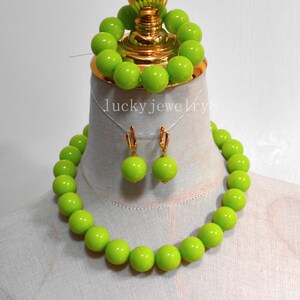 May include: A lime green jewelry set featuring a necklace, earrings, and bracelet. The necklace and bracelet are composed of large, round beads. The earrings have gold-colored hooks. The text "lucky jewelry8" is visible.