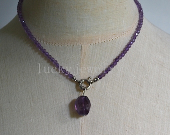 Könnte beinhalten: Eine lila Perlenkette mit Silberverschluss und einem großen, facettierten Amethyst-Anhänger. Die Halskette wird auf einer Schaufensterpuppe präsentiert. Der Text "lucky jewel" ist im Hintergrund sichtbar.